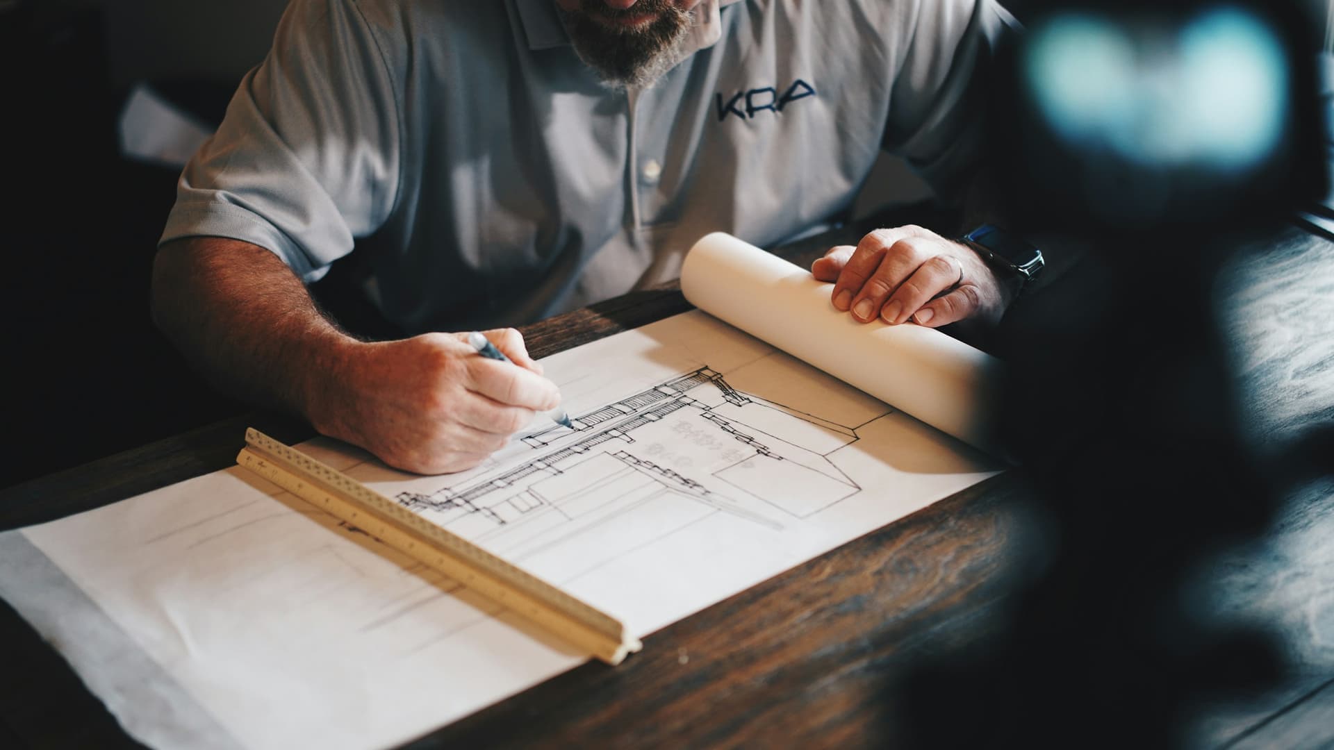 Mains traçant un plan de structure à la règle sur un plan de bâtiment